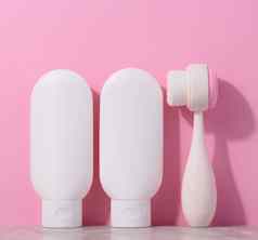 白色塑料管奶油按摩刷面部清洗粉红色的背景项目化妆品程序