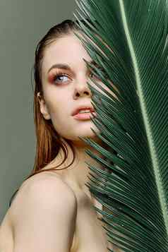 复杂的优雅的女人晚上化妆站绿色棕榈叶覆盖部分脸垂直照片修版