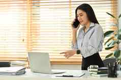 美丽的年轻的女金融顾问电话谈话客户端移动PC办公室