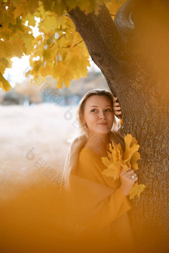 金发女郎站秋天树深思熟虑的女人之前穿着黄色的衣服秋天内容