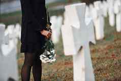 粒子视图年轻的女人黑色的衣服参观墓地白色十字架概念葬礼死亡