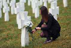 尊重把花年轻的女人黑色的衣服参观墓地白色十字架概念葬礼死亡