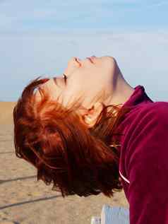 肖像红发十几岁的女孩关闭眼睛空海滩
