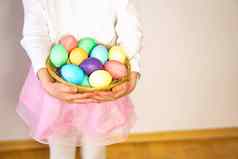 女孩年持有篮子彩色的复活节鸡蛋手