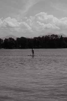 灰度拍摄男人。paddleboarding基姆湖湖巴伐利亚德国阳光明媚的一天