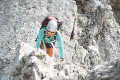女人登山者穿保护头盔攀爬山阳光明媚的一天