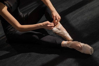 不知名<strong>的</strong>芭蕾舞女演员<strong>坐在地板上</strong>把尖端鞋子前视图