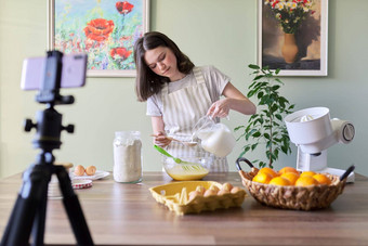 女孩少<strong>年年</strong>轻的食物博主烹饪橙色煎饼倒<strong>牛</strong>奶