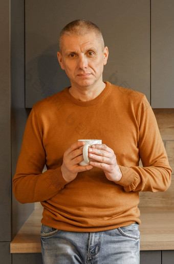 肖像成熟的男人。橙色跳投厨房杯子温暖的茶