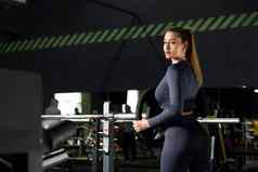成人高加索人女人女运动员把重量板巴贝尔健身房穿蓝色的导管长袖前
