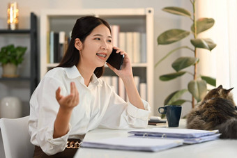 快乐的年轻的女金融顾问愉快的电话谈话享受移动沟通首页办公室