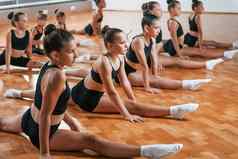 坐着地板上集团女孩子们练习运动练习在室内