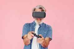 玩游戏虚拟现实眼镜操纵杆时尚的现代高级男人。灰色的头发胡子在室内