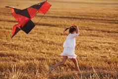 快乐女孩运行红色的风筝在户外场夏季