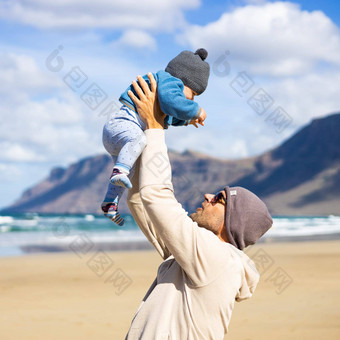 父亲享受纯自然持有玩婴儿婴儿男孩儿子多风的桑迪海滩法马拉兰斯洛特岛西班牙家庭旅行育儿概念