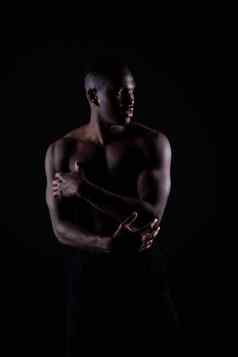 年轻的非洲肌肉发达的构建男人。站袒胸轮廓孤立的黑色的背景