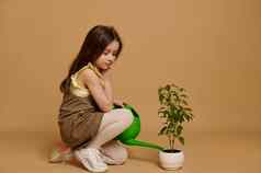 全身的美丽的孩子女孩卡其色衣服倒水花能盛开的辣椒胡椒植物