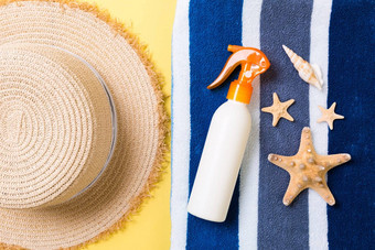 海滩平躺配件复制空间条纹蓝色的白色毛巾贝壳关节遮阳帽瓶防晒霜黄色的背景夏天假期概念