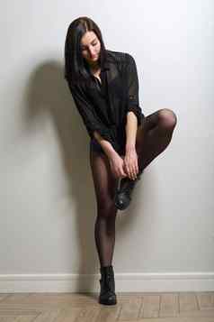 时尚年轻的美丽的女人黑色的连裤袜靴子黑色的上衣