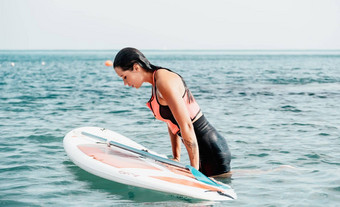 海女人轮廓快乐年轻的女人粉红色的比基尼冲浪董事会自信划水表面田园日落活跃的生活方式海河