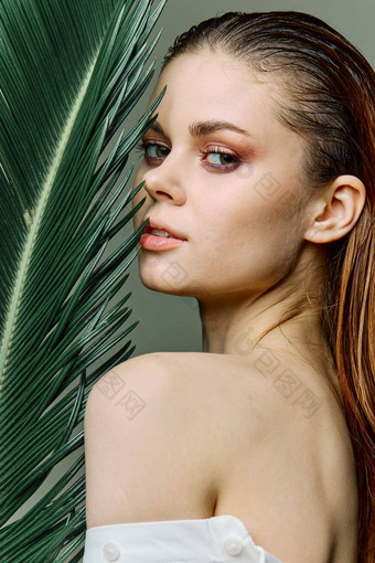 复杂的优雅的女人晚上化妆站绿色棕榈叶覆盖部分脸关闭垂直肖像照片修版