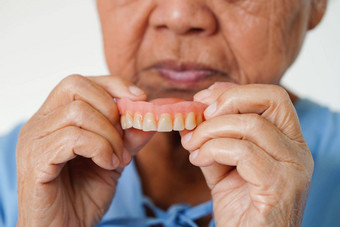 亚洲高级女人病人持有牙齿假牙手<strong>咀嚼食物</strong>