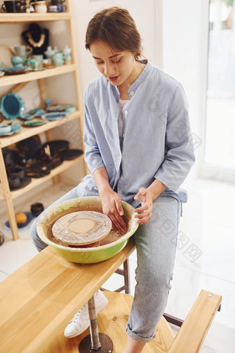 年轻的女<strong>陶艺</strong>家工作陶器轮在室内使手工制作的粘土产品