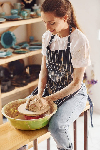 年轻的女陶艺家工作陶器轮在室内使手工制作的粘土产品