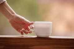 早....咖啡杯女手持有白色杯早....热喝咖啡茶阳台背景山自然