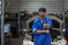 肖像积极的亚洲汽车机械师统一的摆姿势拇指