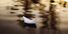 纸船浮动波水美丽的日落折纸船航行概念梦想未来童年自由希望