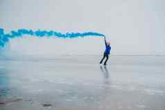 高加索人女人滑冰冻湖持有彩色的蓝色的烟手