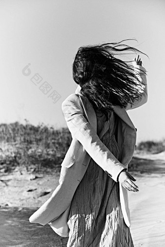 单色照片旋转女人海岸浅色的夹克脸覆盖头发
