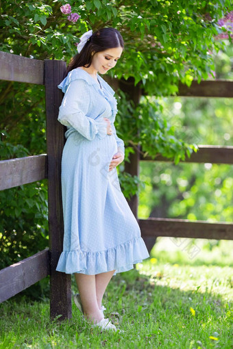 微笑怀孕了女孩蓝色的衣服站木栅栏