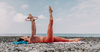 女人海普拉提运动快乐中间岁的女人练习健身海滩海微笑活跃的女培训环瑜伽席享受健康的生活方式和谐冥想
