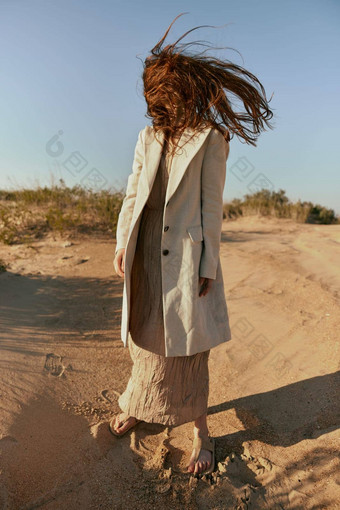 非典型的肖像女人时尚的夏天衣服站金沙头发覆盖脸