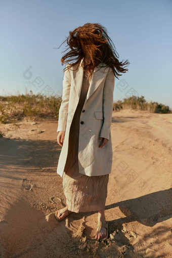 非典型的肖像女人时尚的夏天衣服站金沙头发覆盖脸