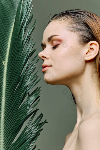 复杂的优雅的女人站绿色棕榈叶持有脸站横盘整理相机眼睛关闭