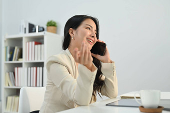 年轻的女商人投资顾问愉快的电话谈话咨询客户端工作桌子上