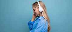 女孩无线大耳机享受放松音乐应用程序蓝色的背景