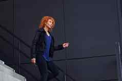 年轻的欧洲红色头发的人女人走楼梯在户外