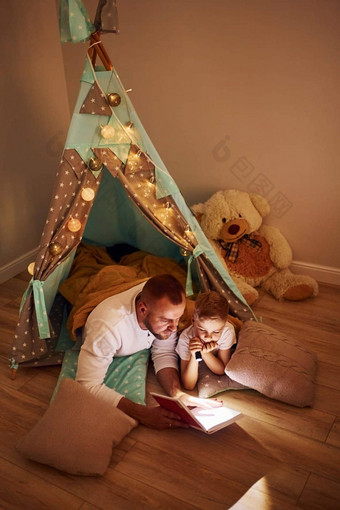 阅读书手电筒父亲年轻的年轻的支出时间在<strong>室内帐篷</strong>