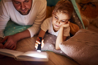 阅读书手电筒父亲年轻的年轻的支出时间在<strong>室内帐篷</strong>