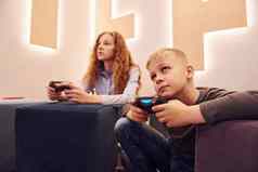 快乐的孩子们坐着在室内玩视频游戏