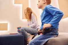 快乐的孩子们坐着在室内玩视频游戏