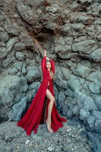 红色的衣服岩石女人金发女郎流动头发长流动红色的衣服站岩石火山起源旅行概念照片会话海