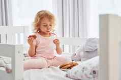 早餐吃饼干可爱的女孩休闲衣服在室内首页白天