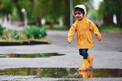 孩子黄色的防水斗篷靴子玩在户外雨