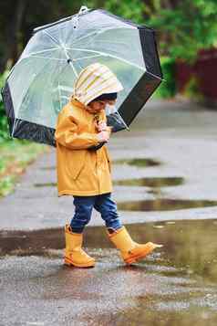 孩子黄色的防水斗篷靴子伞玩在户外雨