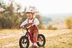 快乐女孩保护他骑自行车在户外阳光明媚的一天森林